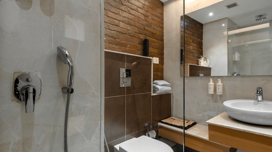 A contemporary bathroom interior featuring a wash basin counter, a large mirror, and an enclosed shower stall at Tiara by MPS.