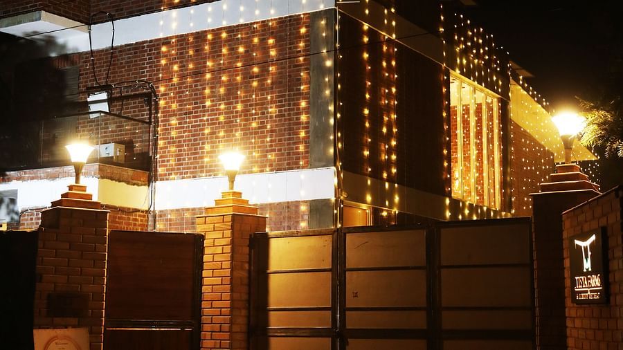 Gated entrance with surrounding wall and building visible at night at Tisya Farms, Gurgaon.