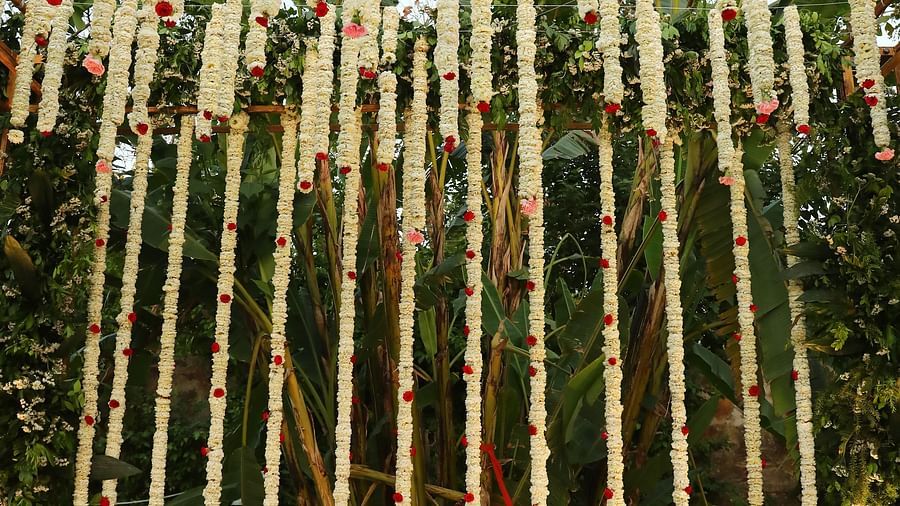 Vertical bamboo poles decorated with flowers at Tisya Farms, Gurgaon, arranged in an outdoor area.