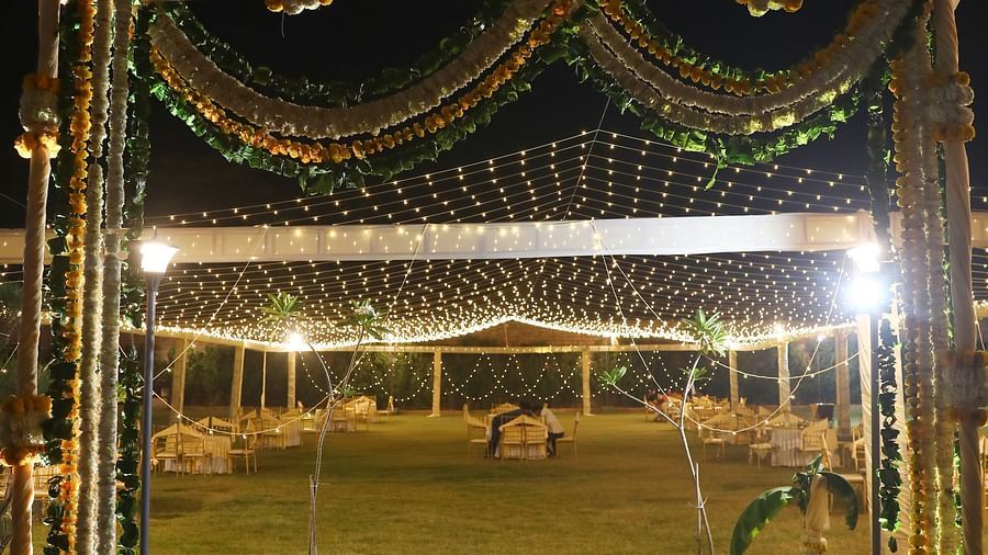 Entrance arch with gold drapes and floral decor on a red carpet at Tisya Farms, Gurgaon.