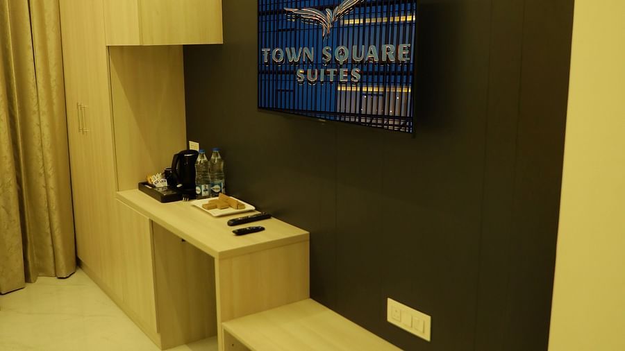 Modern deluxe bedroom at Town Square Suites with flat-screen TV and minimalist furnishings