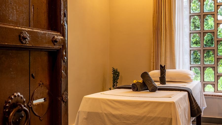 A wooden door opening to the spa with a bed and ambient lighting - Utsav Camp
