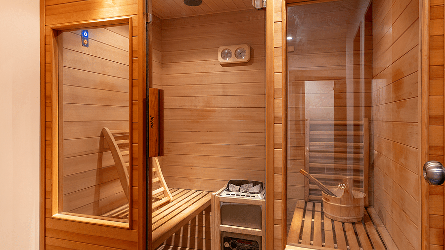 A wooden sauna with a glass door and side panels, lit from above - Via Lakhela Resort & Spa, Kumbhalgarh