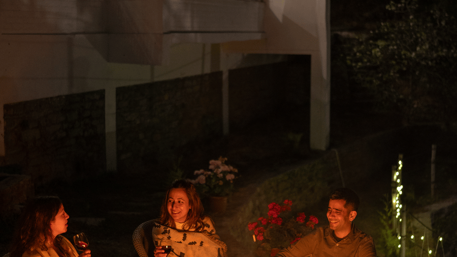 People are gathered around a bonfire in front of a building at Ziran Retreat.