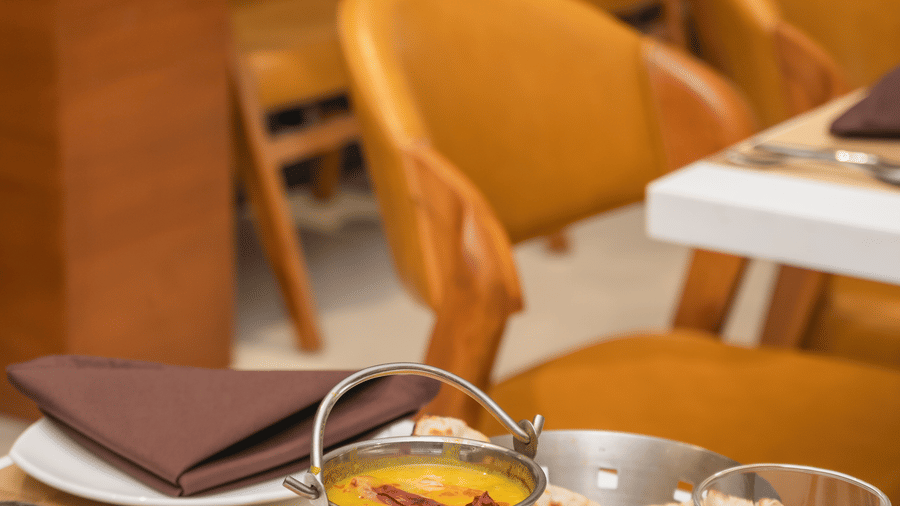 Bowls of food and drinks are arranged on a set table in a restaurant with empty chairs - Lords Eco Inn Ambaji.