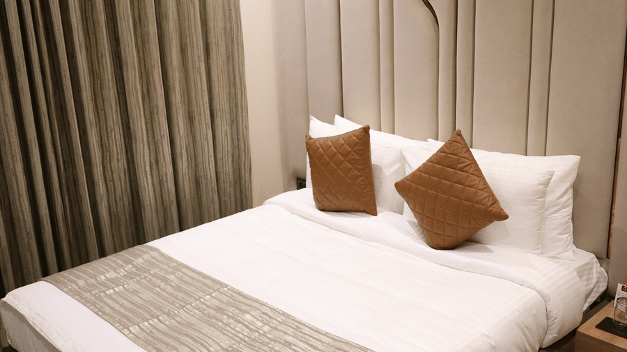 A cosy double bed is tucked neatly beside a stylishly patterned headboard wall - Lords Inn Sangam, Bhopal