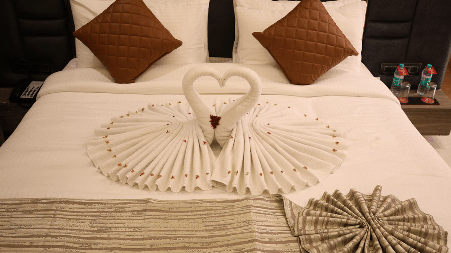Beautifully folded towels decorate a double bed flanked by brown pillows - Lords Inn Sangam, Bhopal