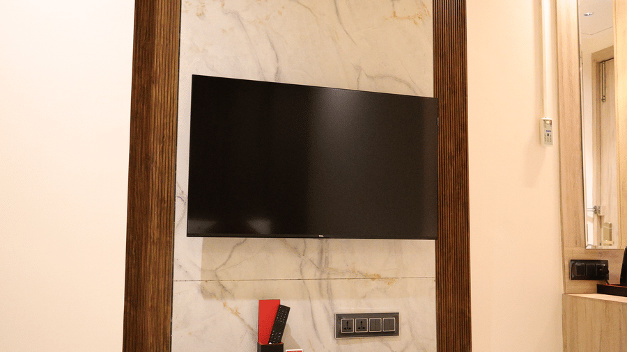 A sleek television is neatly mounted on a modern wooden wall feature panel - Lords Inn Sangam, Bhopal