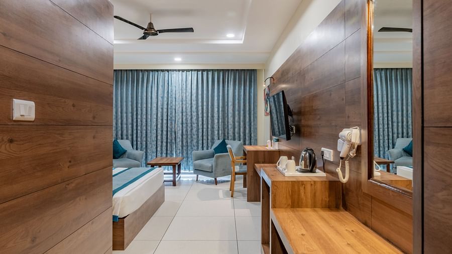 Hallway perspective of a hotel room with king size bed, wooden flooring, and ambient lighting at Hotel Highway King, Bilaspur.