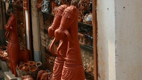 A red statue of two dogs in front of a store