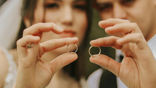 Image of newlyweds holding up wedding rings