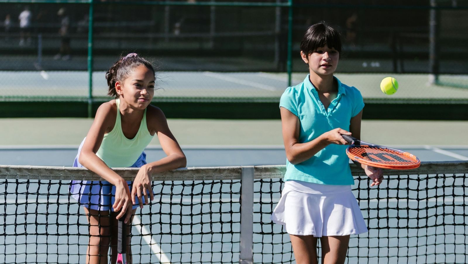 Two women holding tennis rackets on an outdoor tennis court