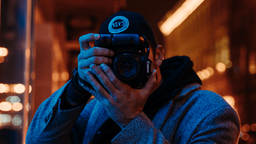 A potrait of a photographer taking pictures while his face is hidden behind the camera.