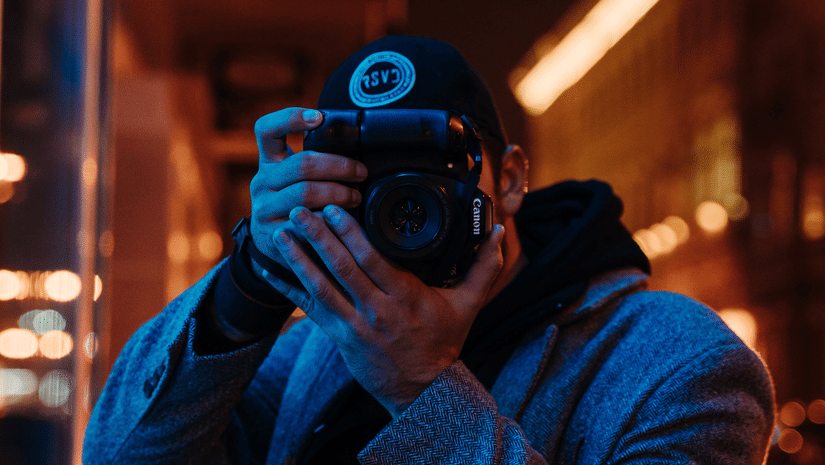 A potrait of a photographer taking pictures while his face is hidden behind the camera.