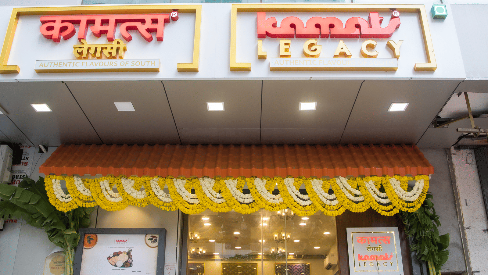 Entrance of Kamats Legacy Malad decorated with floral garlands, featuring a warm, welcoming facade and traditional South Indian design elements.