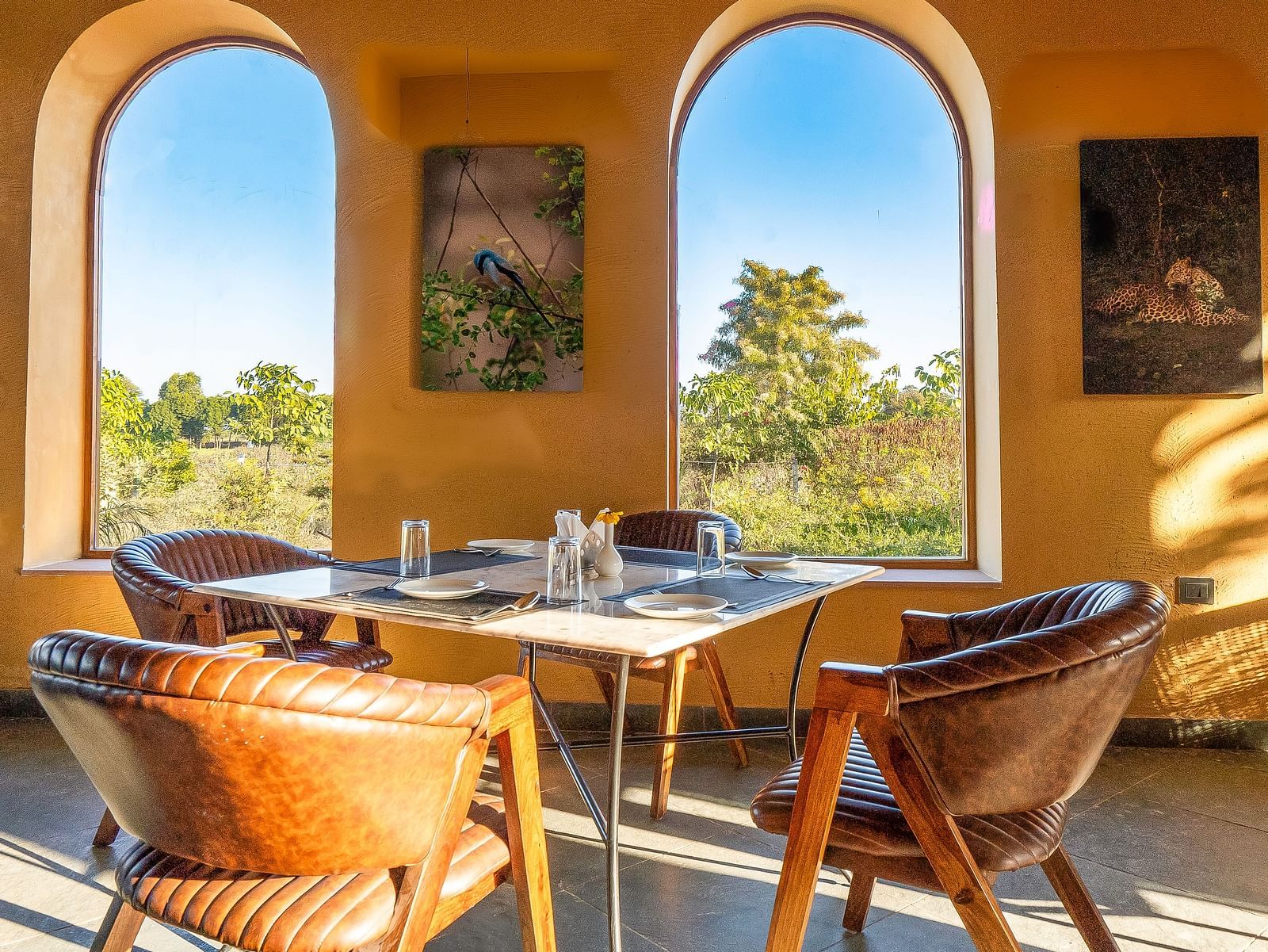 An image of L cave restaurant with tables and chairs in boho theme where sunlight is seeping in and there are two open entrances - Kurja Jawai
