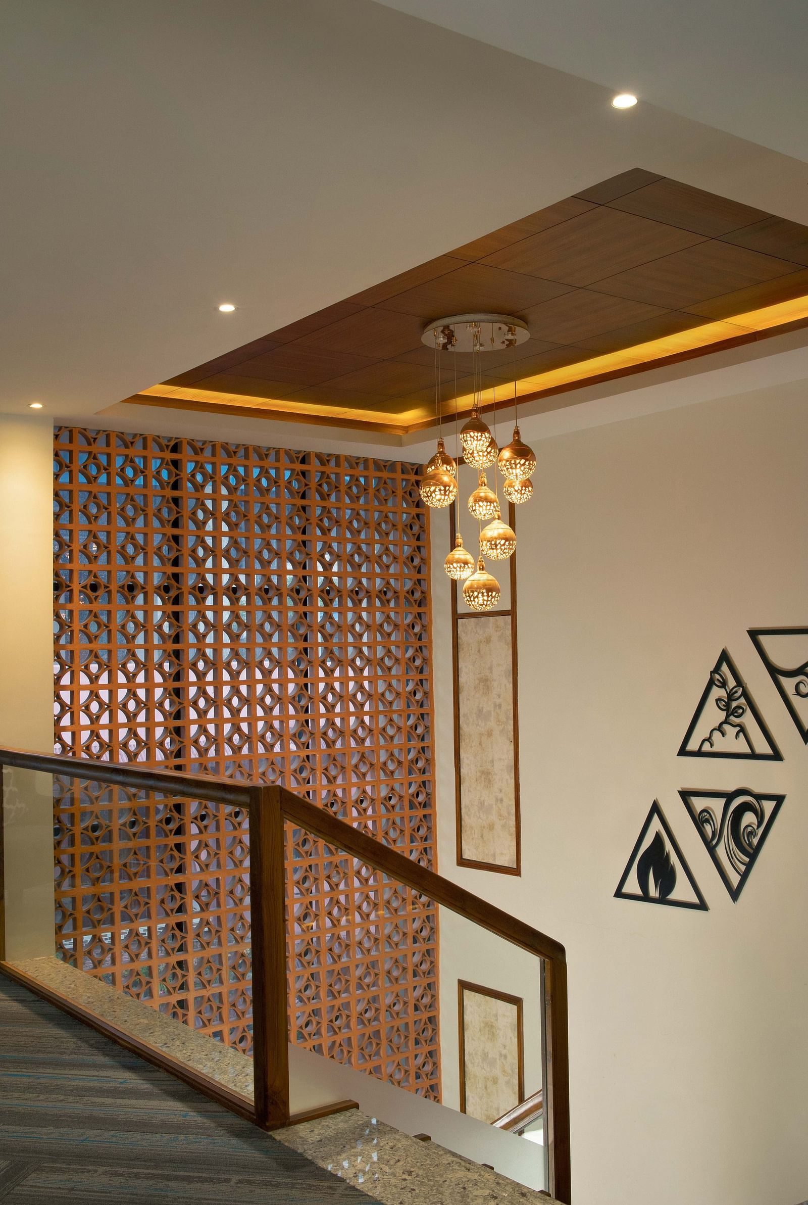 Image of a chandelier hanging from warmly lit ceiling as the wall next to it is adorned with showpieces