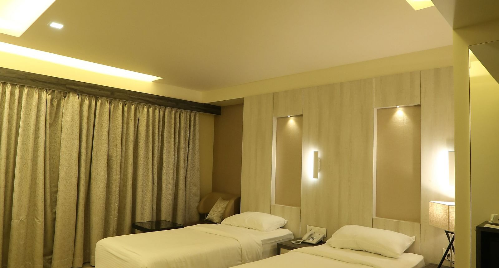 Executive Room with a vanity area, including a mirror and a sink, illuminated by warm lighting, with a chair and beige wall visible.