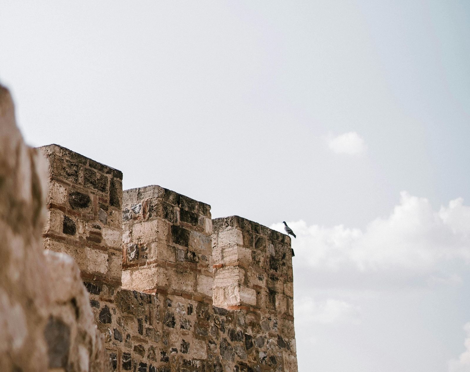 A close up shot of a fortress wall with a clar blue sky in the background.