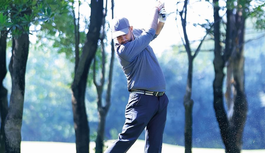 Picture of a man  swinging the club in the bright day light.