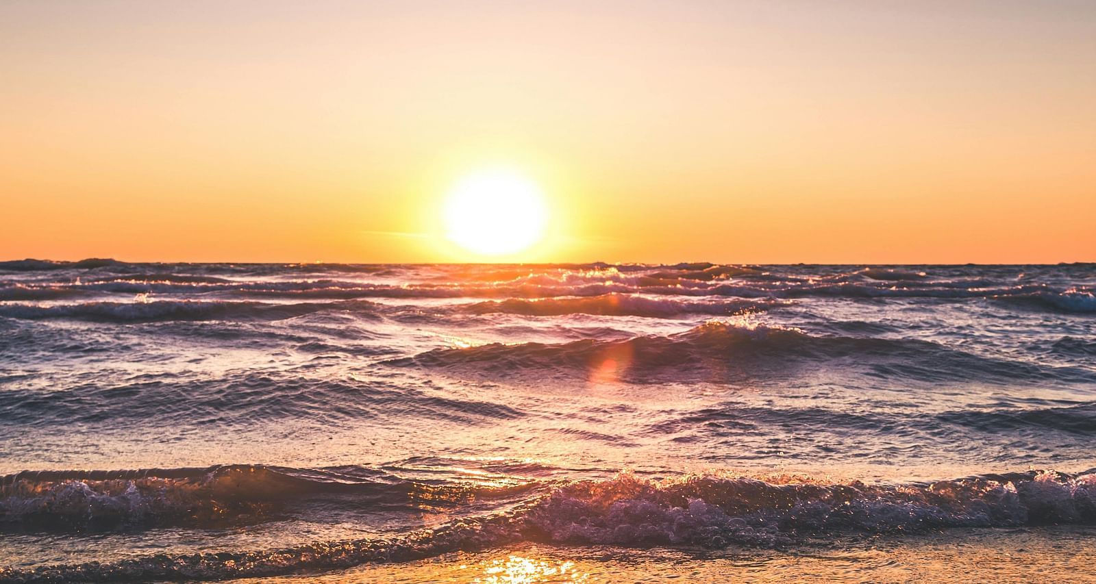 a beautiful sunset during the early evening hours with the bright sun dipping into the ocean