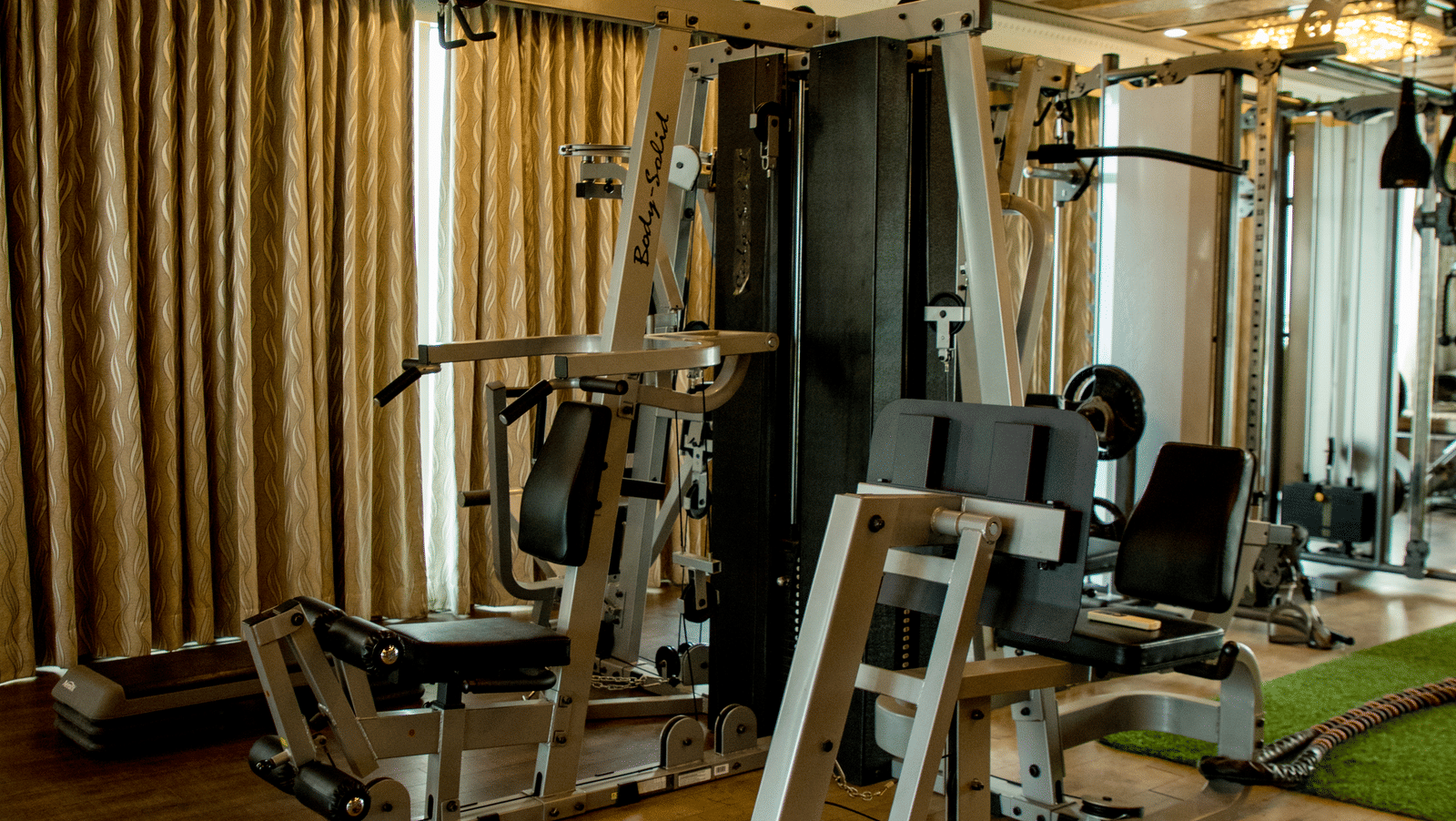 The fitness centre at the Benzz Park, Vellore, featuring a fitness equipment in dimly lit interiors.