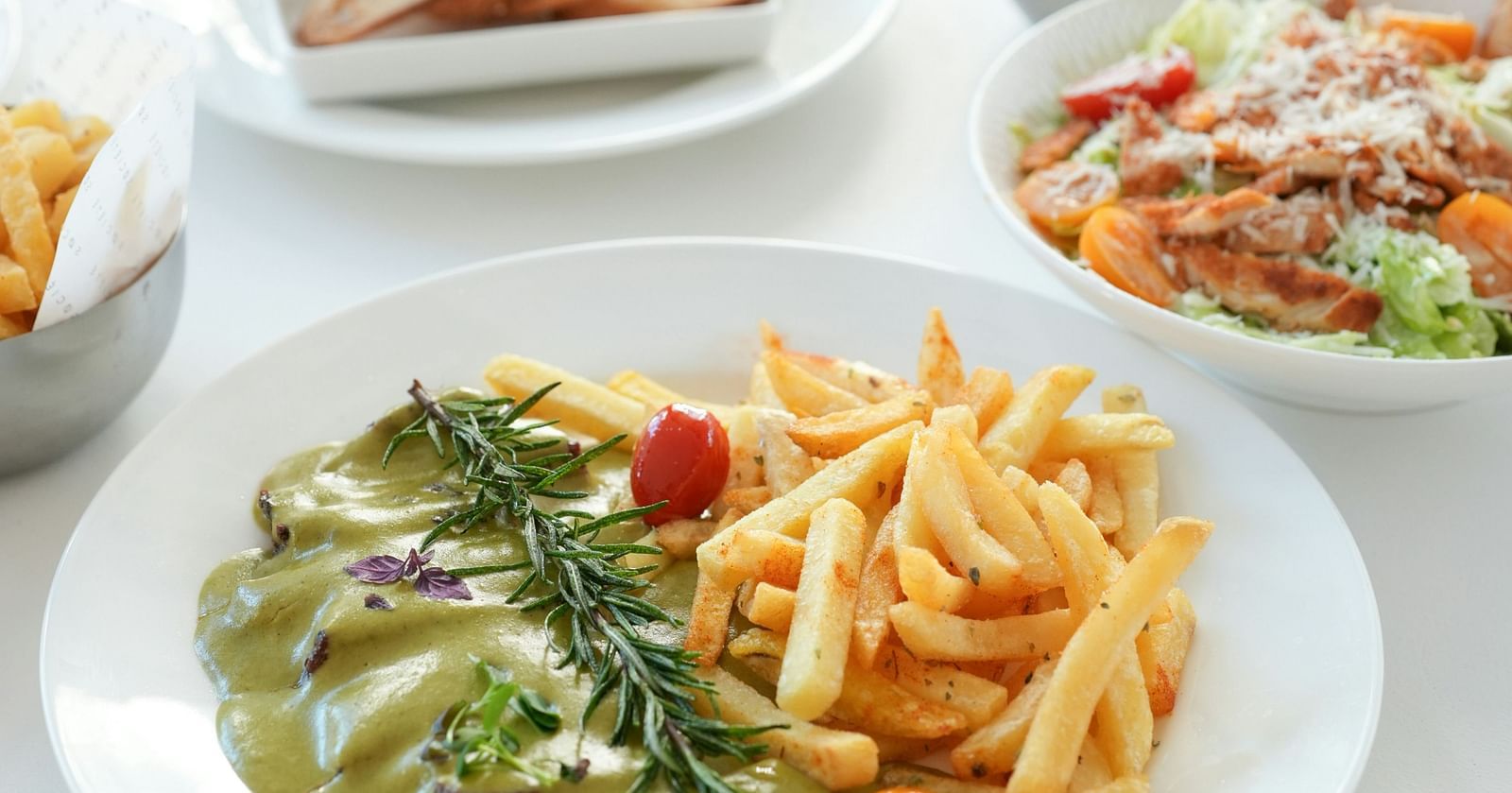 A table with an assortment of dishes including french fries, salad, and bread.