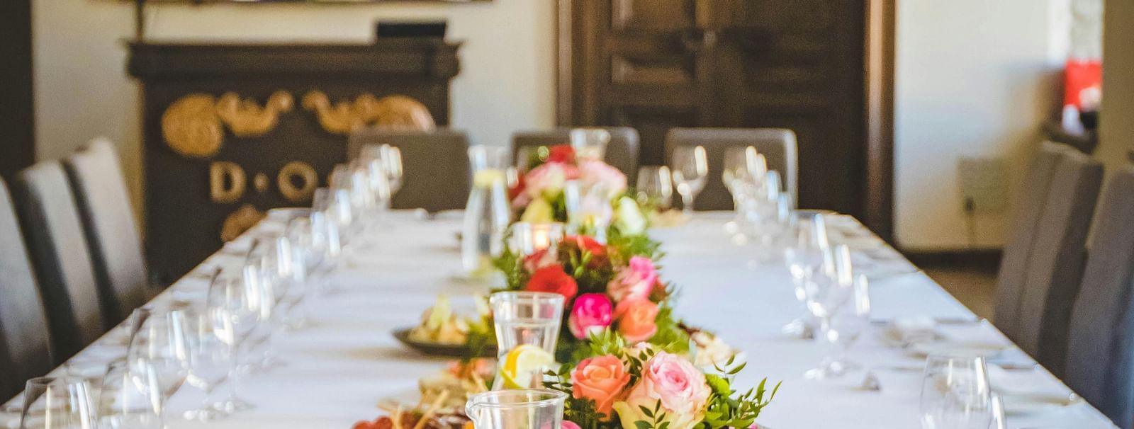 image of a closed space with an expansive dining table decorated with flowers and crockery