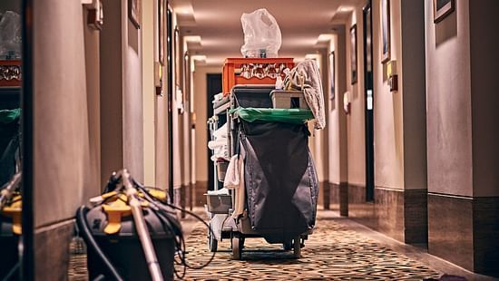 A housekeeping cart in a hotel corridor with patterned carpeting