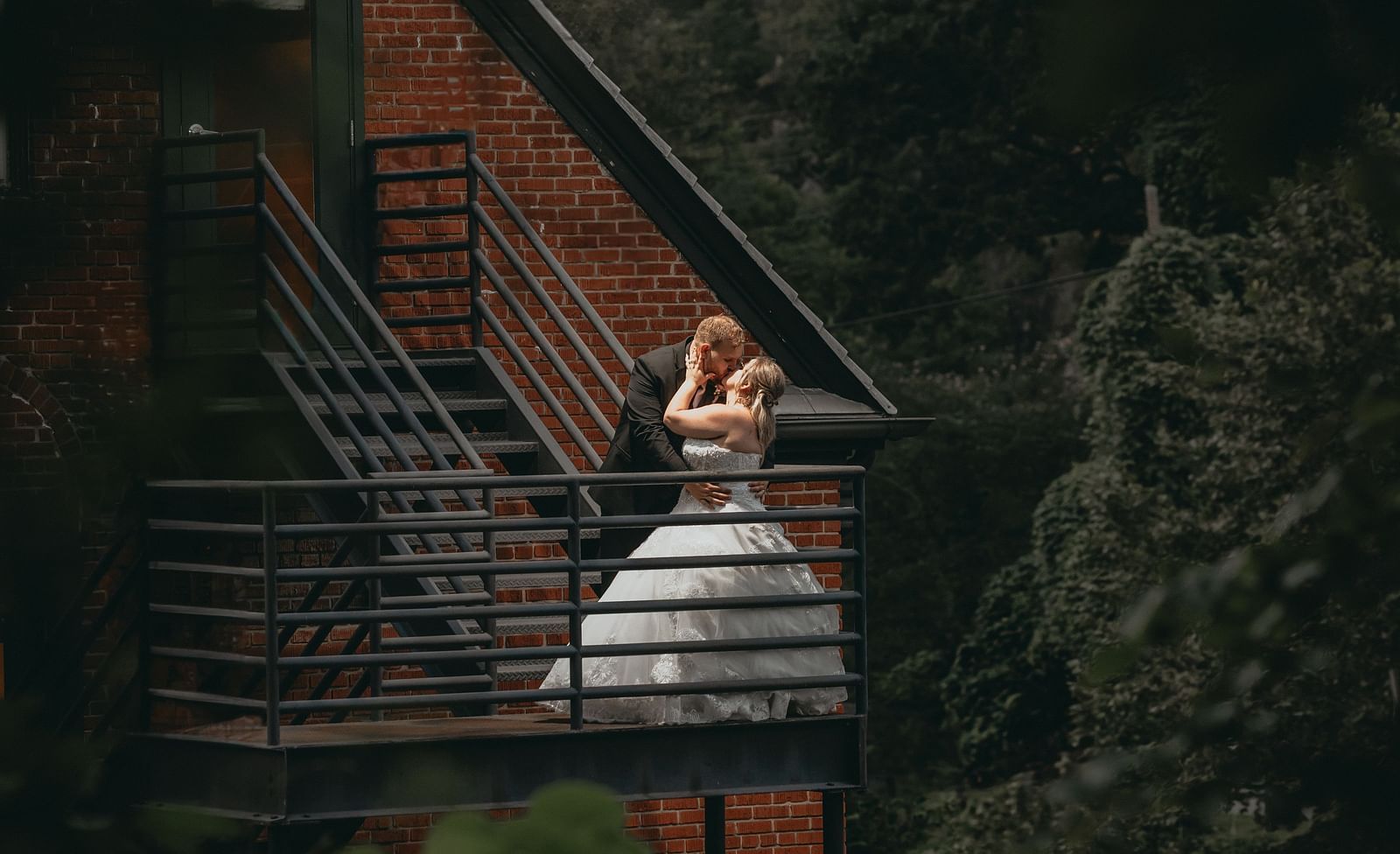 A couple standing on the stairs and kissing each other. The stairs is leading to the cottage of the Historic Tapoco Lodge.