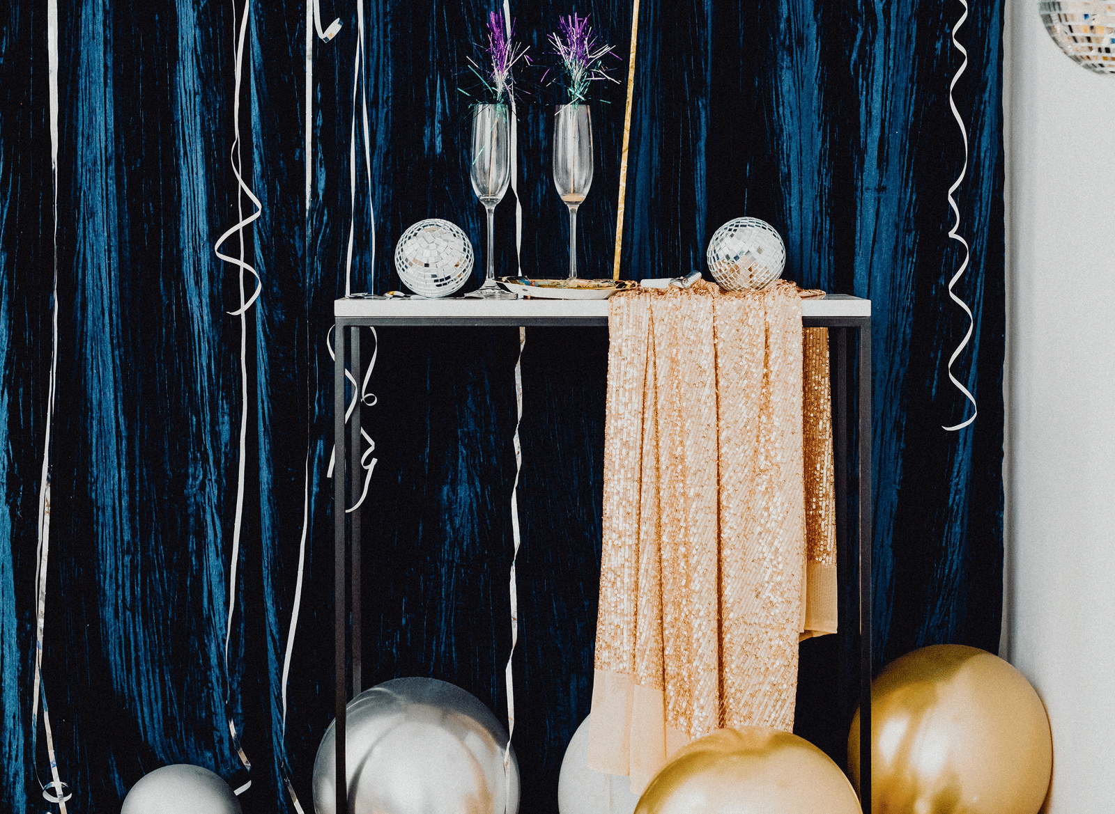 A celebration setup featuring balloons and decorative elements arranged in front of a draped backdrop curtain.