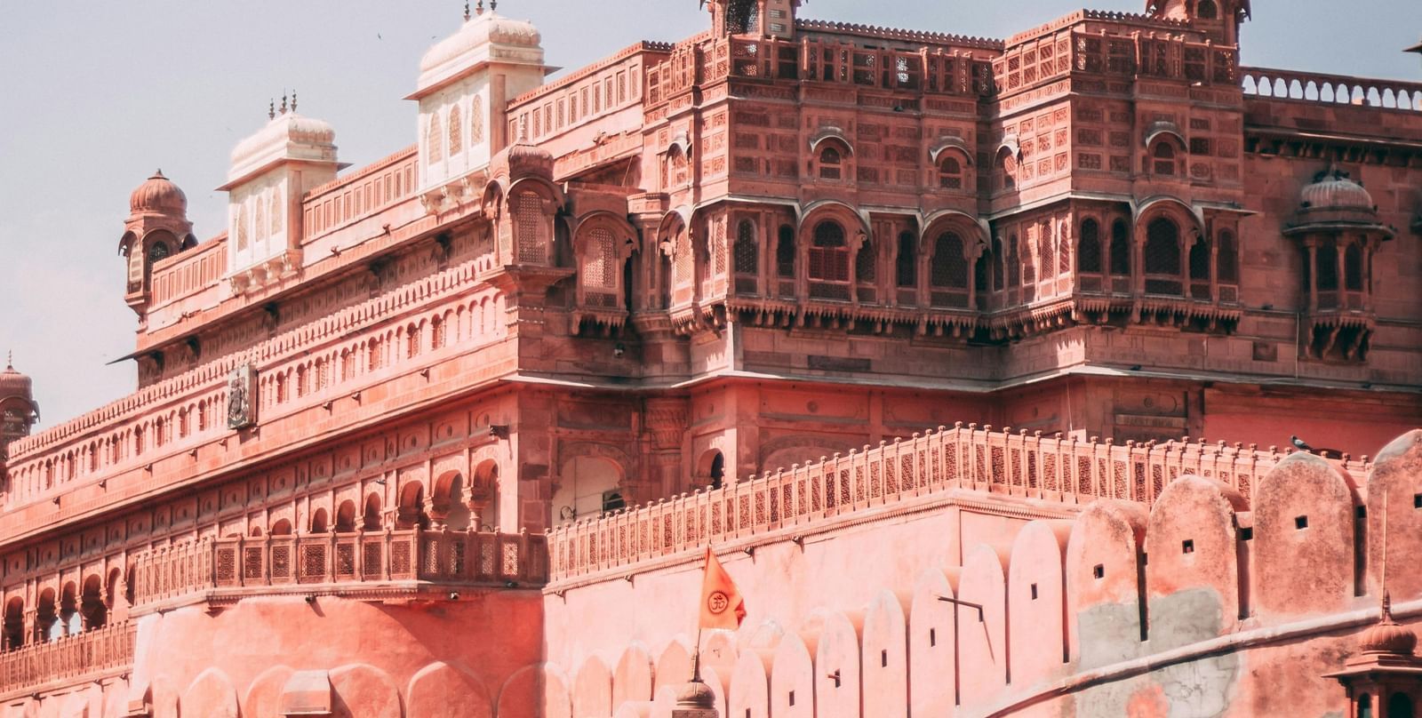 Exterior of a grand pink-hued palace or fort under a clear sky.
