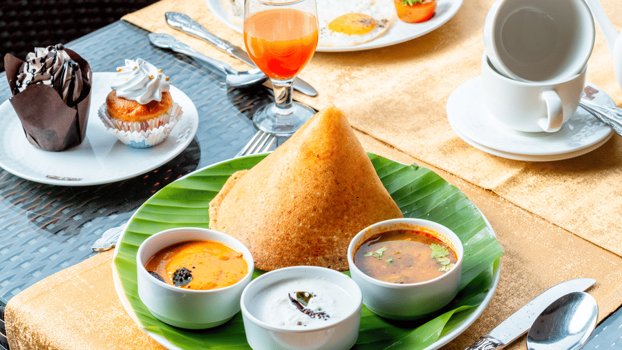 A close-up shot of a plate with Dosa served along with sambhar and chutneys along with a plate featuring English breakfast at the Marble Arch restaurant at Noor-Us-Sabah Palace, Bhopal.