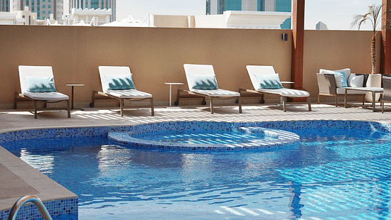 an overview of the swimming pool with sun's rays hitting the swimming pool - La Maison Hotel, Doha