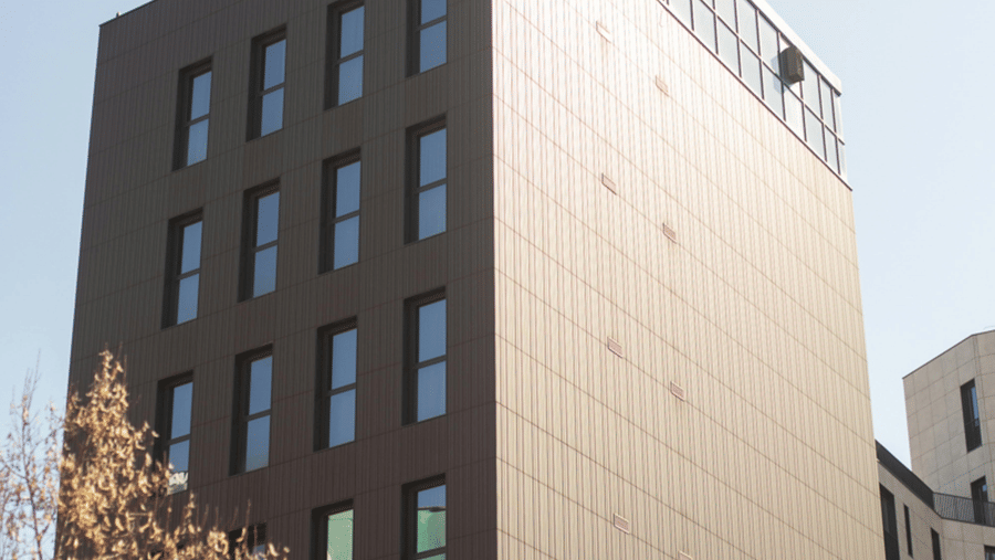 A tall rectangular building with rows of windows stands against a clear sky.