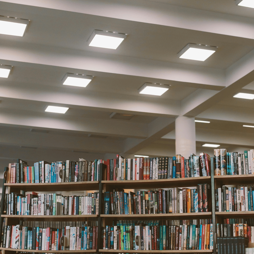 A vertical shot of a library bookshelf filled with books, with a ceiling visible above.