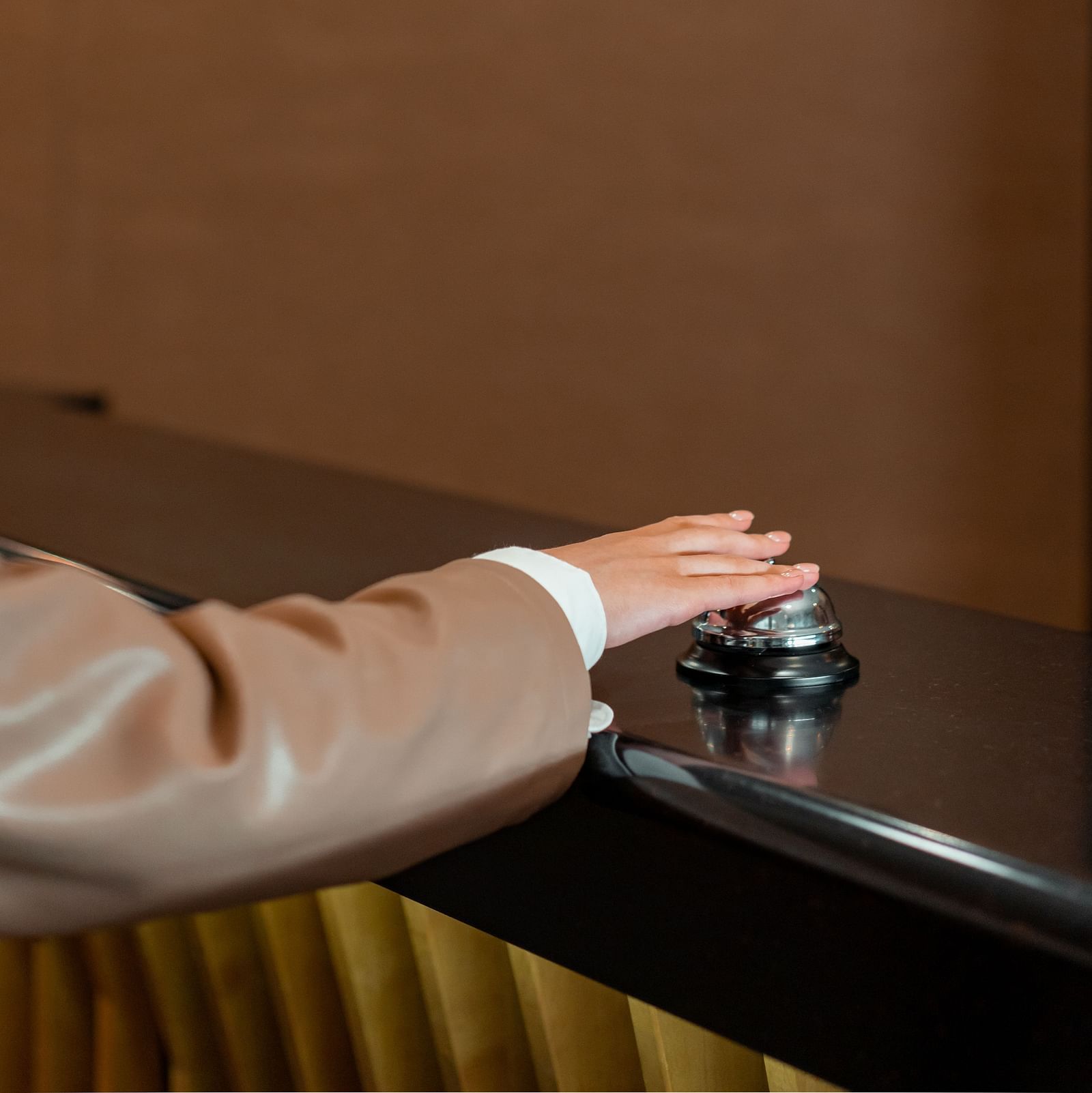 A person hitting a call bell at a hotel reception