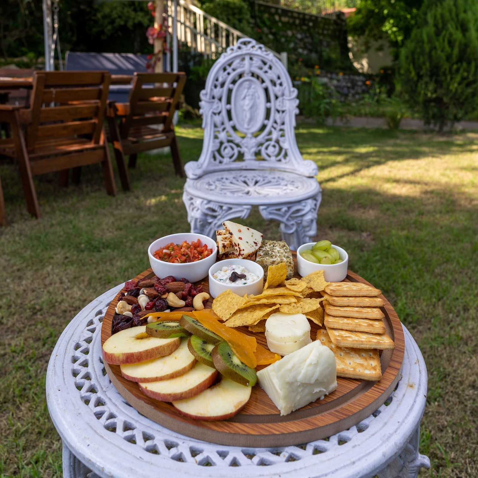 fruits, biscuts, nuts and bread with a dip all arranged on a plate placed on a table
