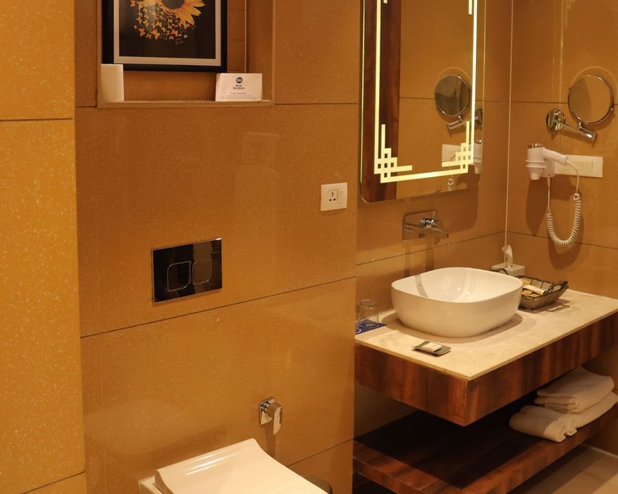 bathroom with modern fixtures, with marble surfaces, wall decor and gold-framed mirror at Best Western, Vrindavan.