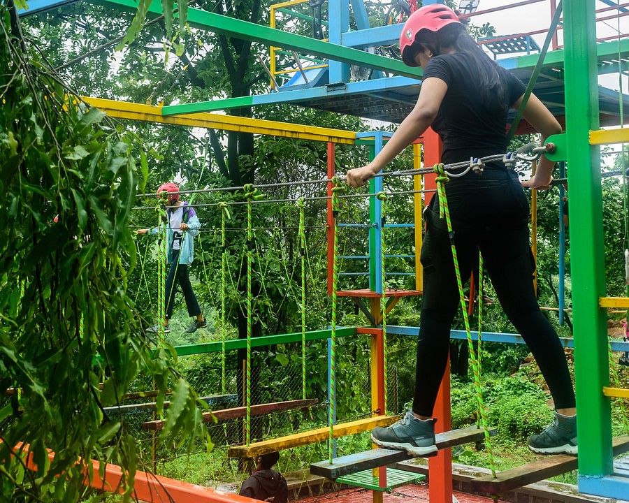 alt-text A portrait of a girl on a burma bridge with helmets and safety equipments making her way across the walkpath