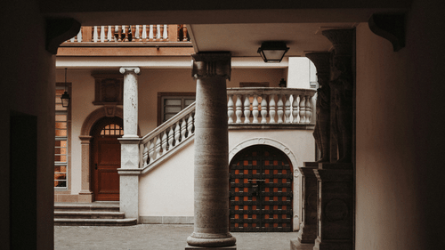 Interior of a traditional Kerala building with pillars and stairs.
