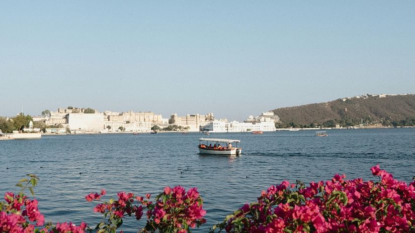 Lake Pichola framed by vibrant bougainvillea with a boat sailing across.