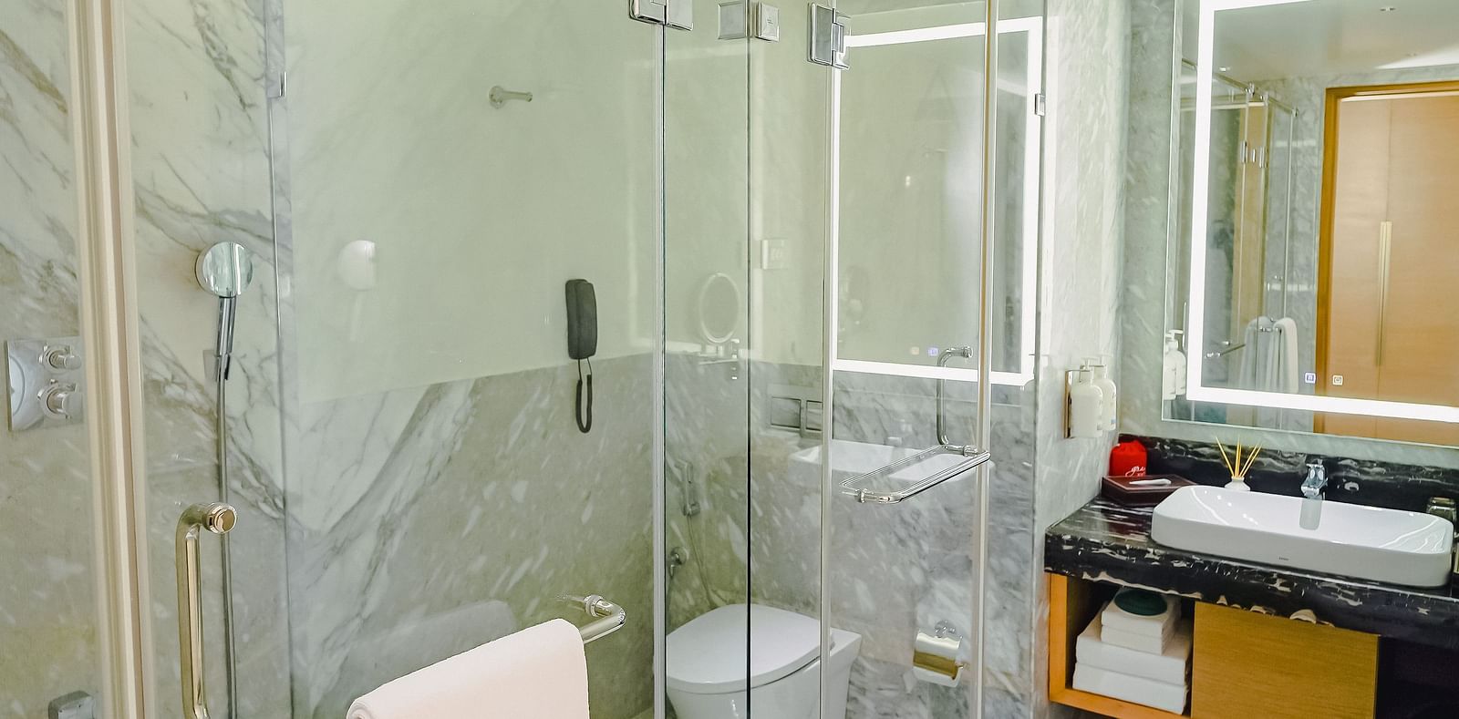 An image of a modern bathroom with a shower cubicle, a large sink and a wall-mounted mirror