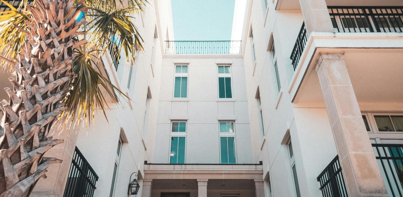 A low-angle shot of a white building with arched doorways under a bright blue sky.