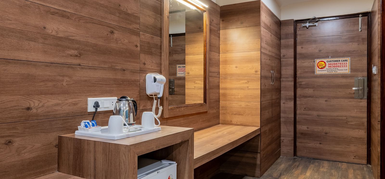 Minibar and wardrobe setup with wooden finish inside a room at Hotel Highway King, Bilaspur.