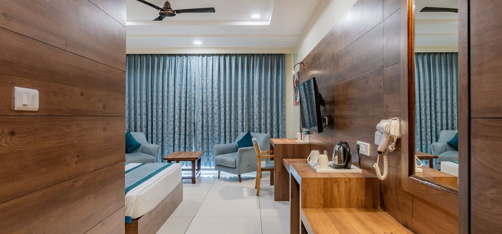 Hallway perspective of a hotel room with king size bed, wooden flooring, and ambient lighting at Hotel Highway King, Bilaspur.