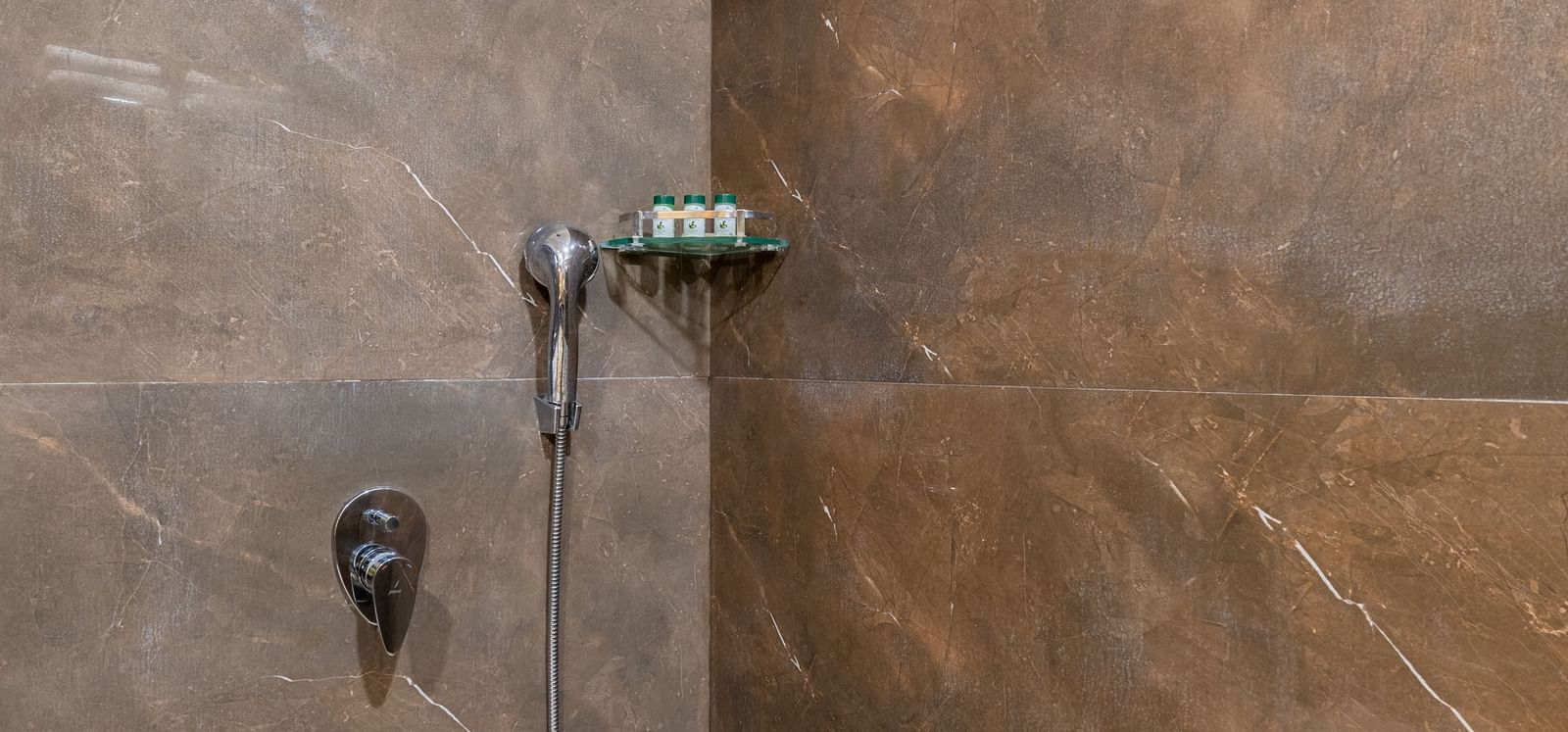 Modern bathroom with rain shower and stone-tiled walls at Hotel Highway King, Bilaspur.