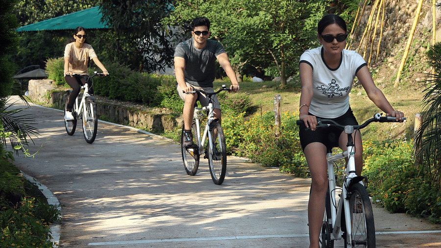 A group of people cycling on a pathway at A man flying a kite at The Sylvan Retreat, Dehradun.