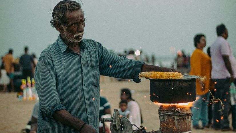 A man roasting corn on a beach.