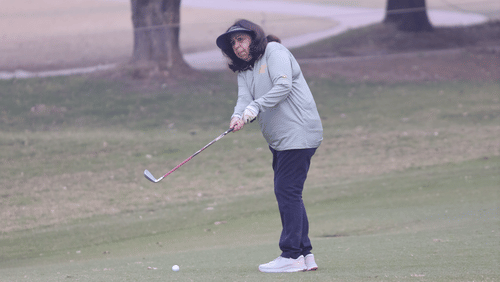 A women playing golf in a vast area with two trees behind her.- Heritage Village Resorts & Spa